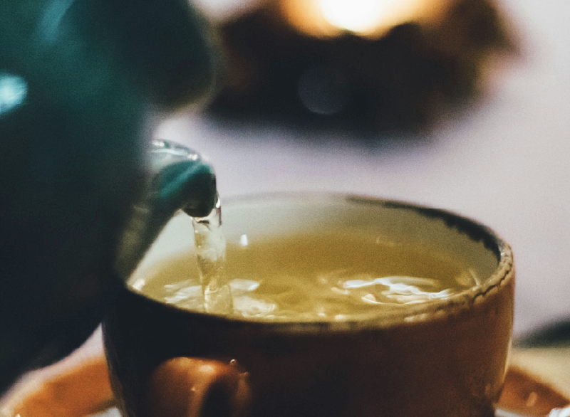 Teal tea spout being poured into a teacup